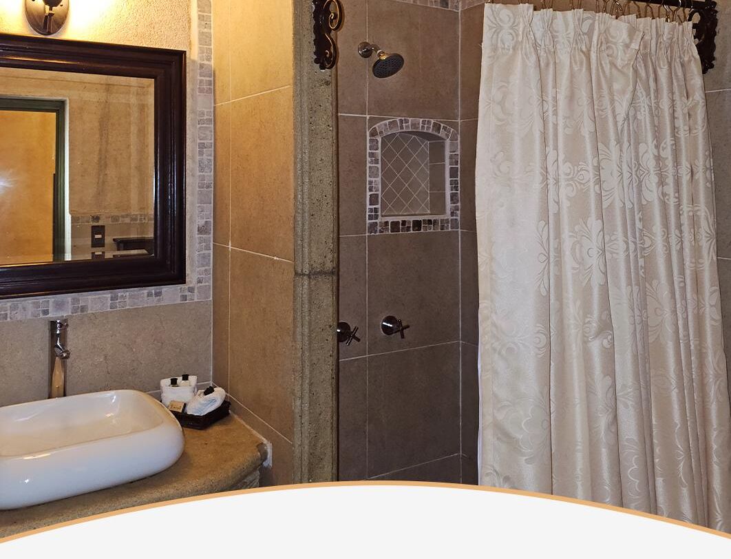 A bathroom with a white sink, a mirror, a shower with a glass door, and a curtain.