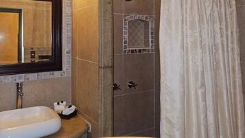A bathroom with a white sink, a mirror, a shower with a glass door, and a curtain.
