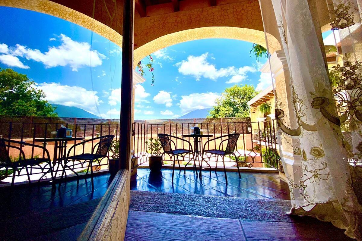 A patio with a pool table, chairs, and a view of the sky and mountains.