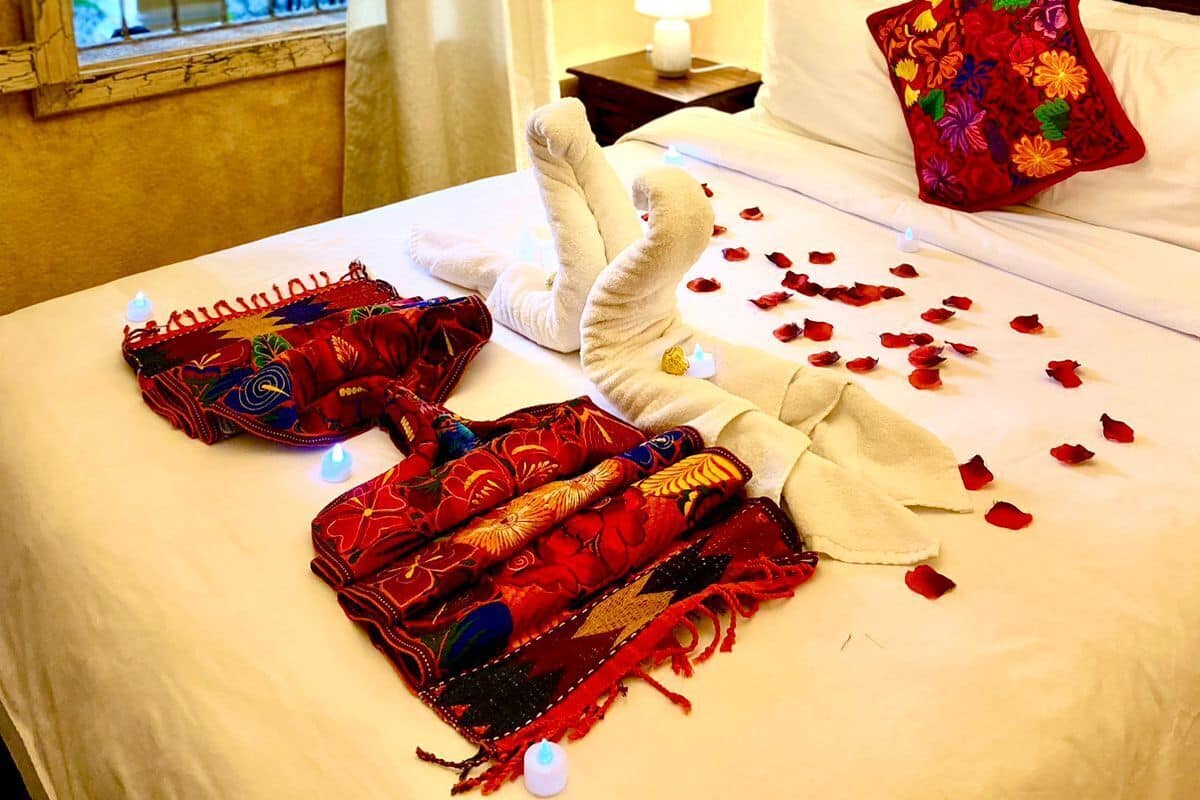 A hotel room with a bed, a window with a curtain, a bedside lamp, and a decorative pillow.