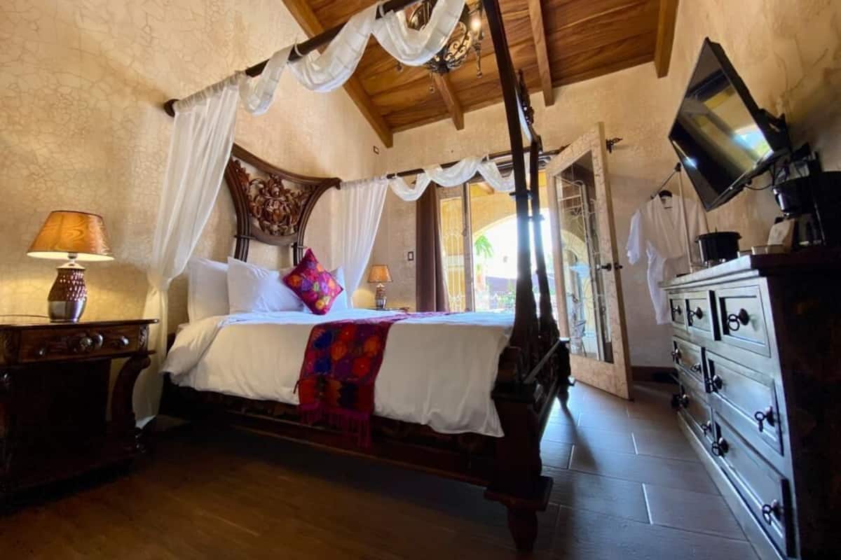 A traditional wooden bed with a canopy, a bedside table with a lamp, and a dresser with drawers.