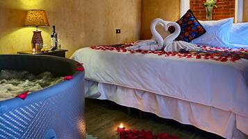 A hotel room with a bathtub, a bed with rose petals and a heart-shaped towel, and a sign for Casa Realiza Hotel.