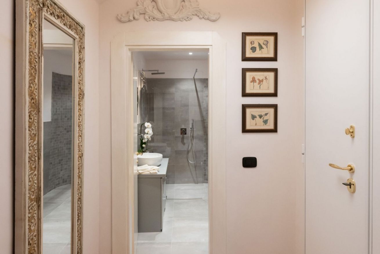 A modern bathroom with a glass shower, a sink, and a toilet. There are framed pictures on the wall.