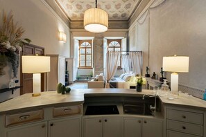 A spacious bathroom with a large sink, two wall-mounted lamps, and a decorative ceiling.