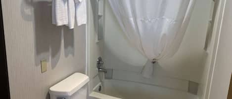 A bathroom with a toilet, a bathtub, and a shower curtain.