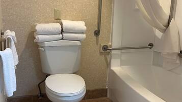 Un baño con inodoro, bañera y cortina de ducha.