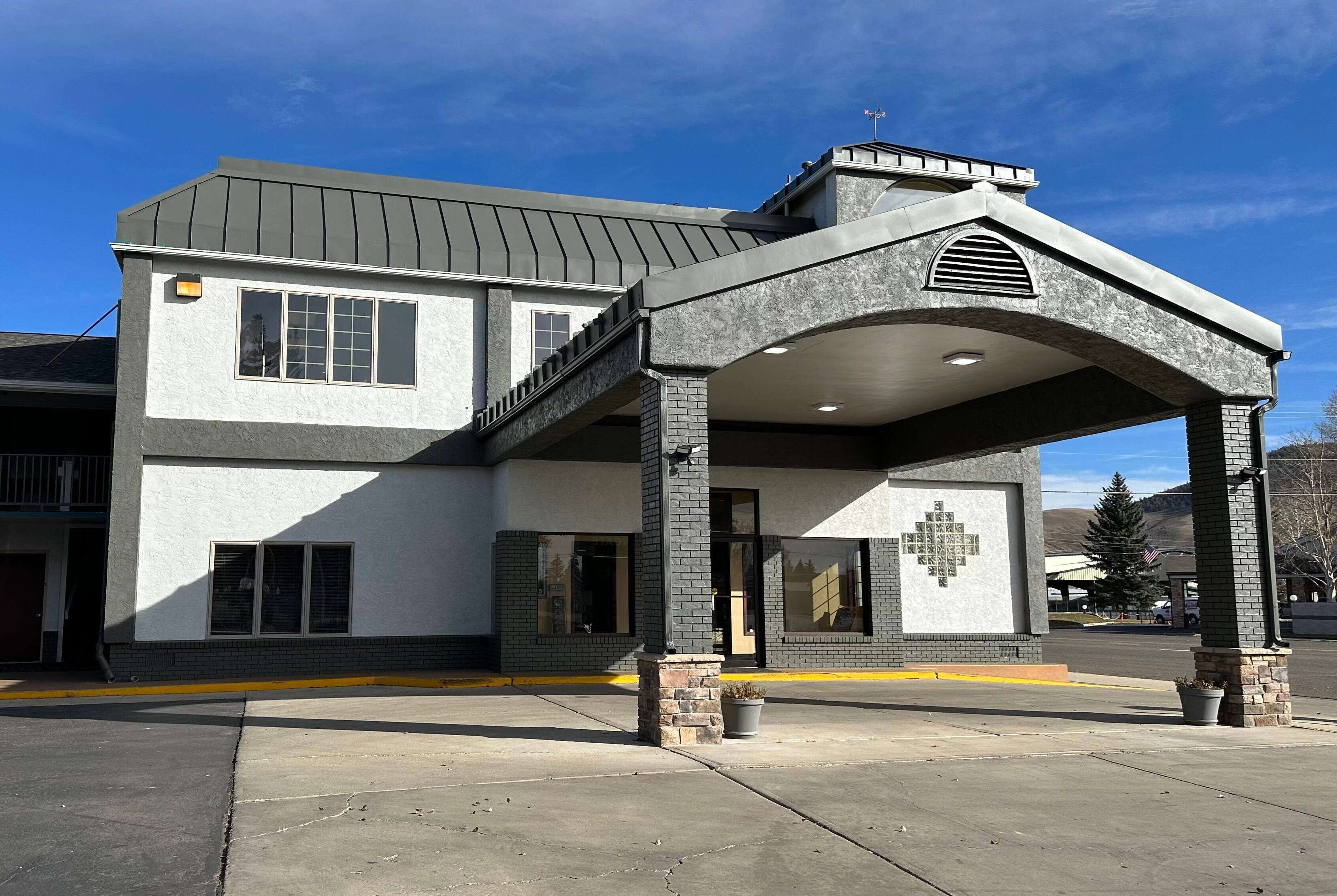 A two-story building with a covered entrance and a cross mural on the wall.