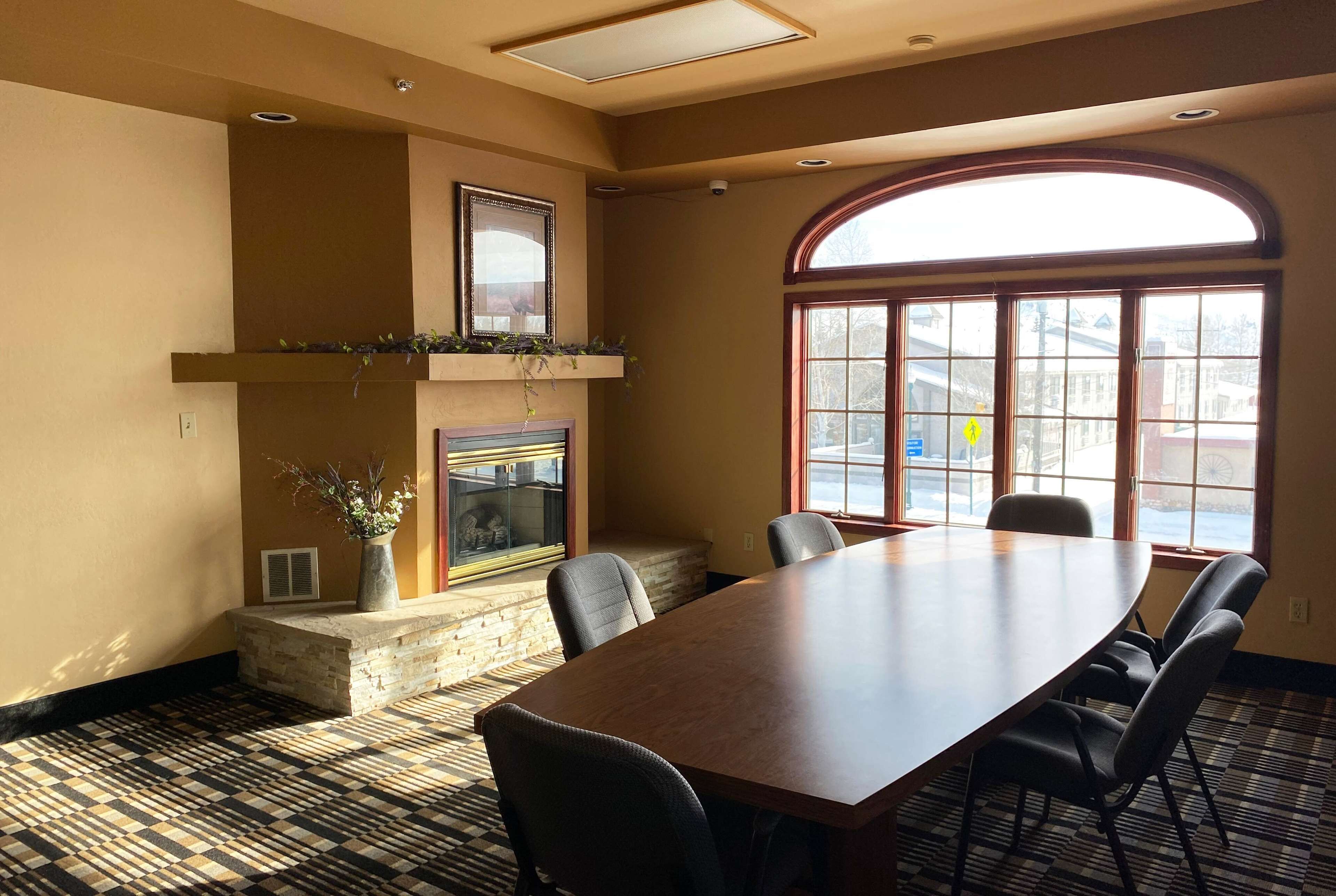 A conference room with a large table, chairs, a fireplace, and a large arched window.