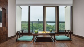 A room with a wooden floor, two green cushioned chairs, a small table with a chessboard, and a view of a forest through large windows. - Howard Johnson By Wyndham Dongqian Lake Plaza Ningbo (Ningbo)