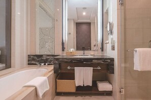 A modern bathroom with a freestanding bathtub, a large mirror, and a dark wood vanity.