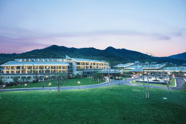 A large hotel with multiple floors and a well-maintained lawn in front.