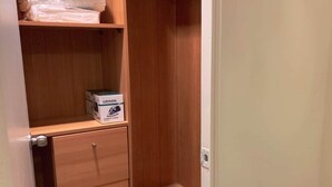A wooden closet with shelves, a hanging rod, and a storage cabinet.