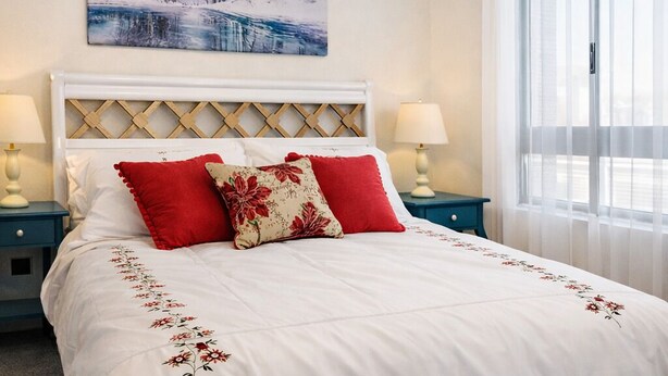 A bedroom with a large bed, a chandelier, a painting, and a window with curtains.