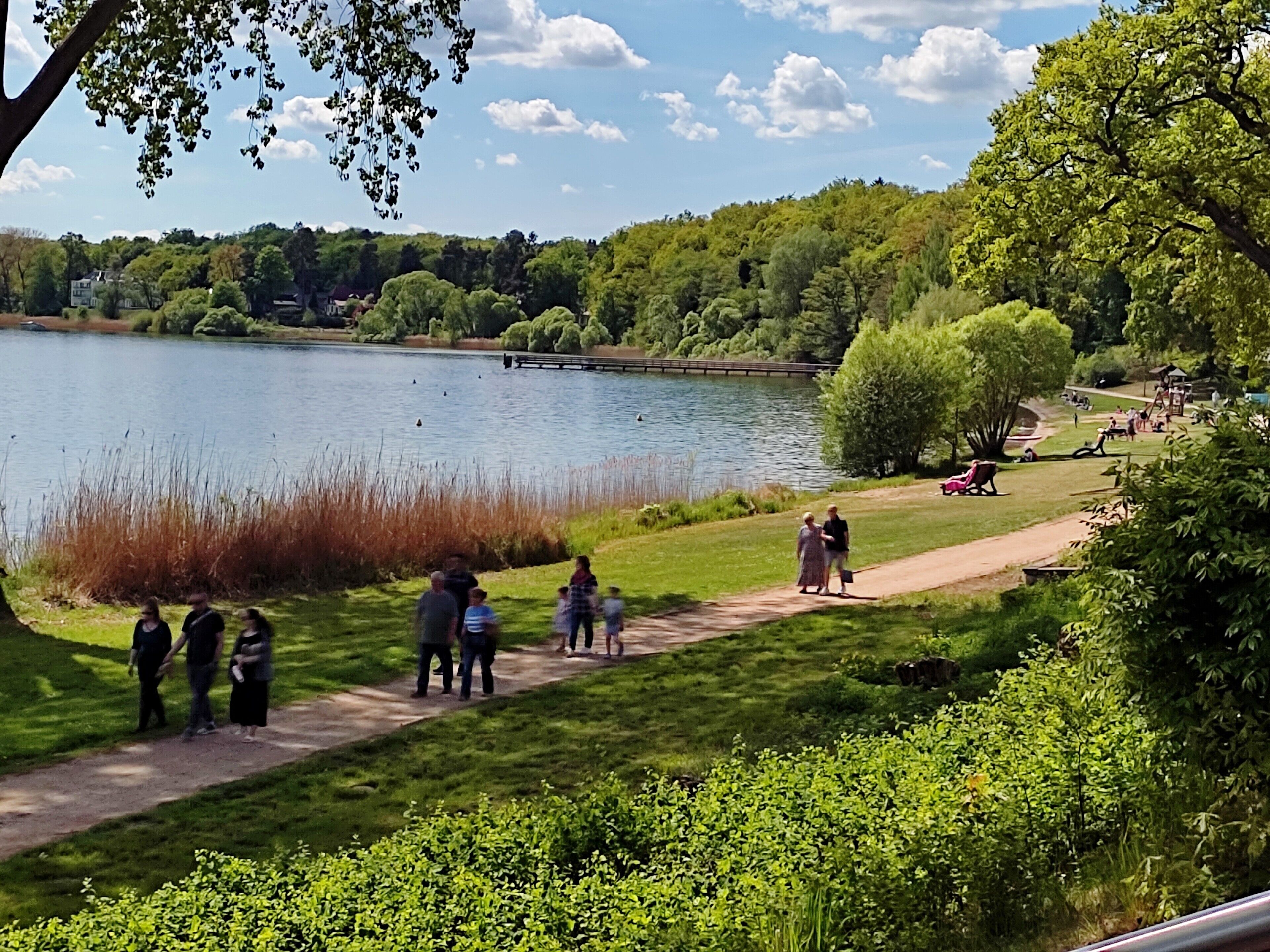 Ein Park mit einem See, Spazierwegen und Menschen.