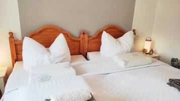 A double bed with a wooden headboard, white bedding, and a wall-mounted picture.