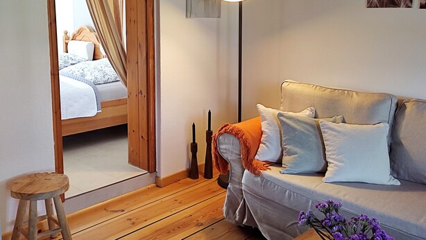 Une pièce avec un lit, un canapé, un lampadaire et un plancher en bois.