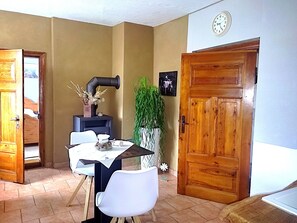 Un coin repas comprenant une table, des chaises, une horloge et une porte en bois.