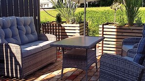 Une terrasse extérieure aménagée avec des meubles en osier, une table et un grand parasol.