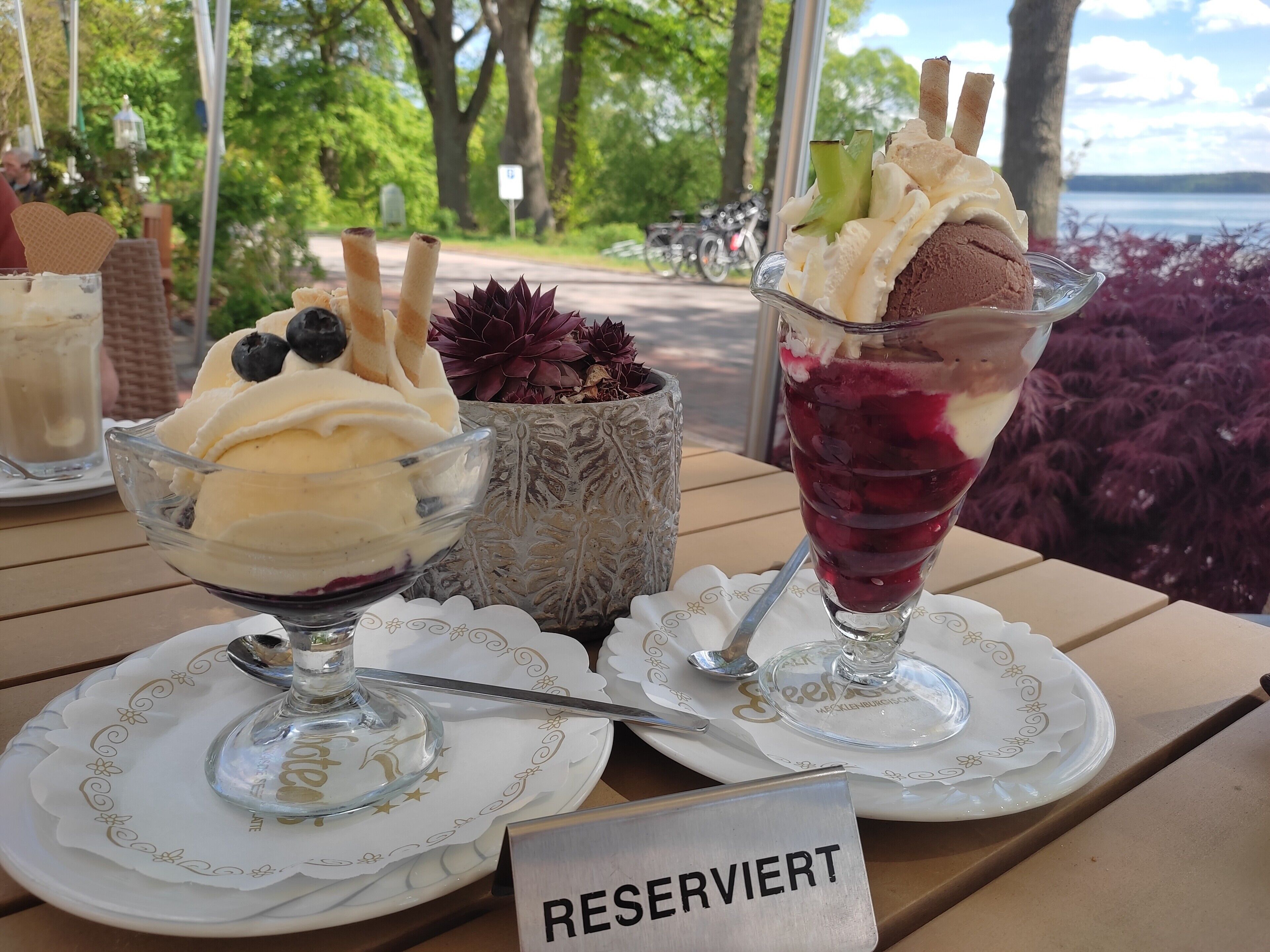 Ein Tisch mit zwei Dessertschalen, einer Kerze und einem Schild mit der Aufschrift 'RESERVIERT'.