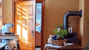 Une cuisine avec une porte en bois, une machine à café, une cuisinière et une table à manger avec des chaises.