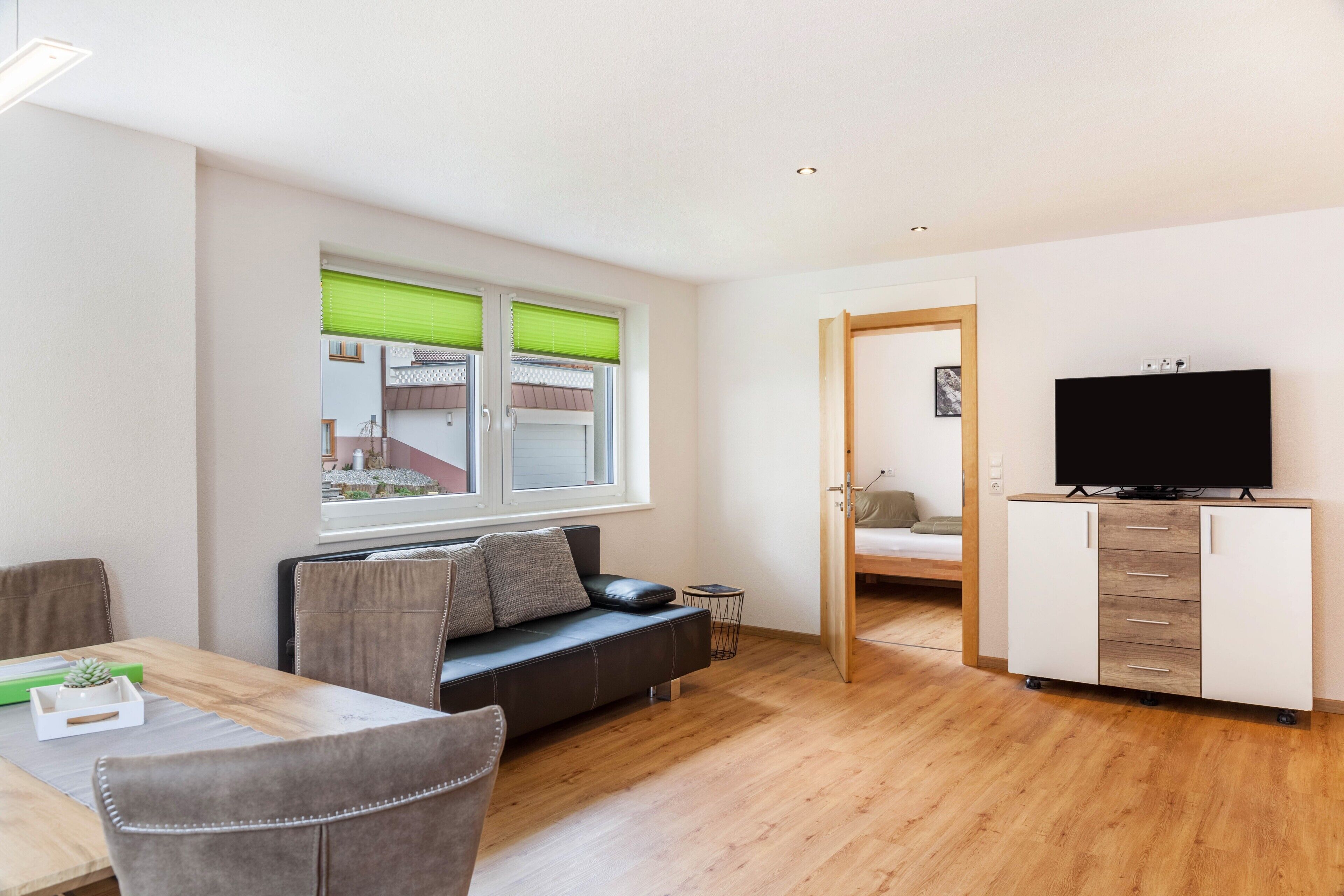 A modern living room with a sofa, dining table, and TV stand.