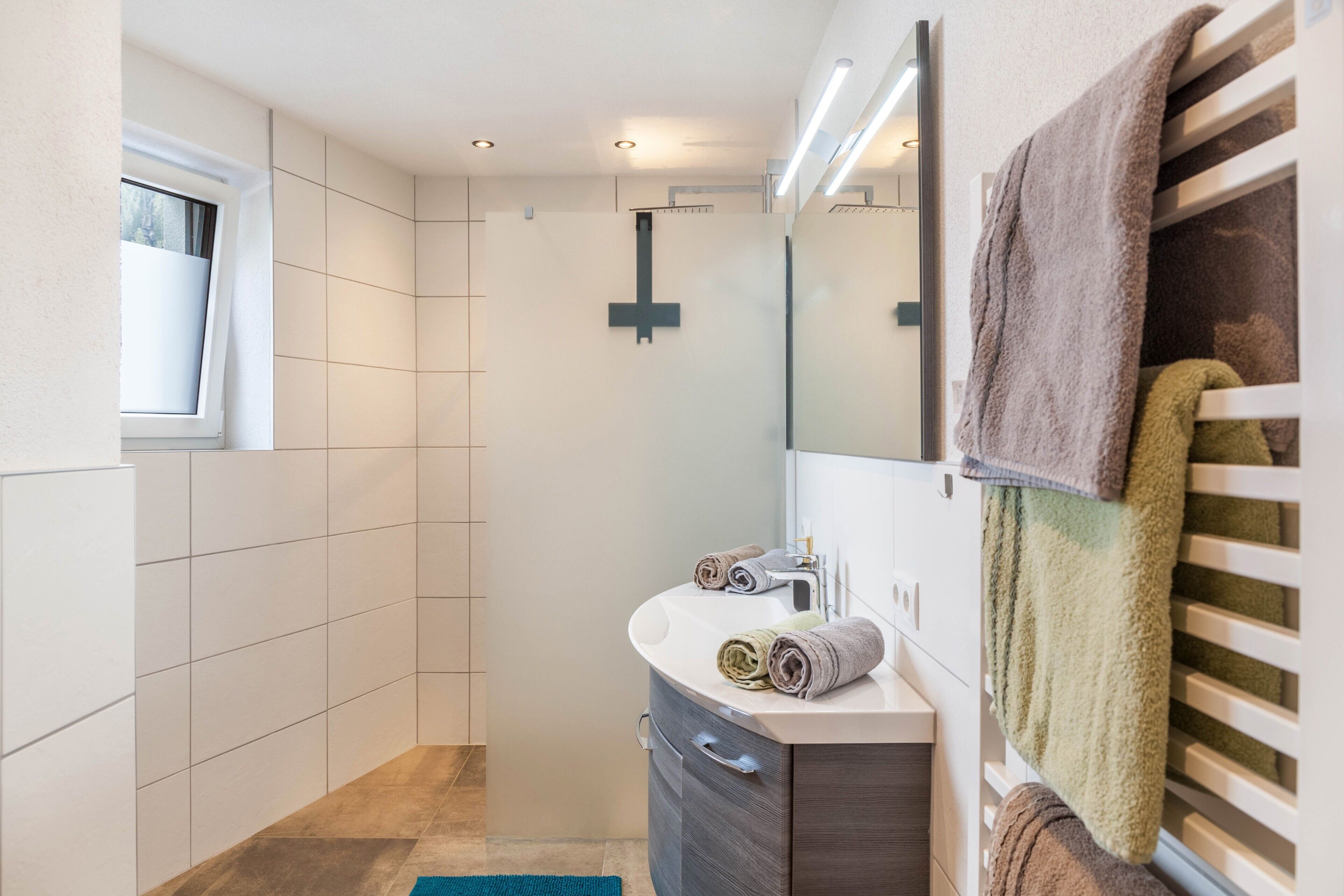 A modern bathroom with a shower, a sink, a mirror, and towels.