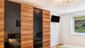 Ein Schlafzimmer mit einem Bett, einem Kleiderschrank, einem Fernseher und einem Fenster mit Blick.