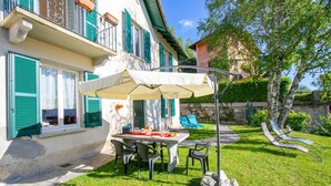 A house with a patio table, chairs, and an umbrella. - Mila Bike & WIFI: Garden Retreat near Lake Maggiore, Pollino di Premeno, Italy (Pollino di Premeno)