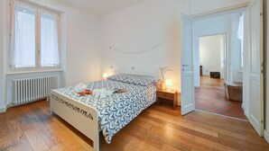 A bedroom with a bed, bedside table, lamp, radiator, window, and wooden floor. - Mila Bike & WIFI: Garden Retreat near Lake Maggiore, Pollino di Premeno, Italy (Pollino di Premeno)