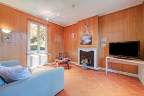 A living room with a sofa, a fireplace, a television, and a window. - Mila Bike with wi-fi, Pollino di Premeno, Italy (Pollino di Premeno)