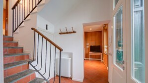 A staircase with red and grey steps, a white radiator, and a wooden door with a glass panel. - Mila Bike & WIFI: Garden Retreat near Lake Maggiore, Pollino di Premeno, Italy (Pollino di Premeno)
