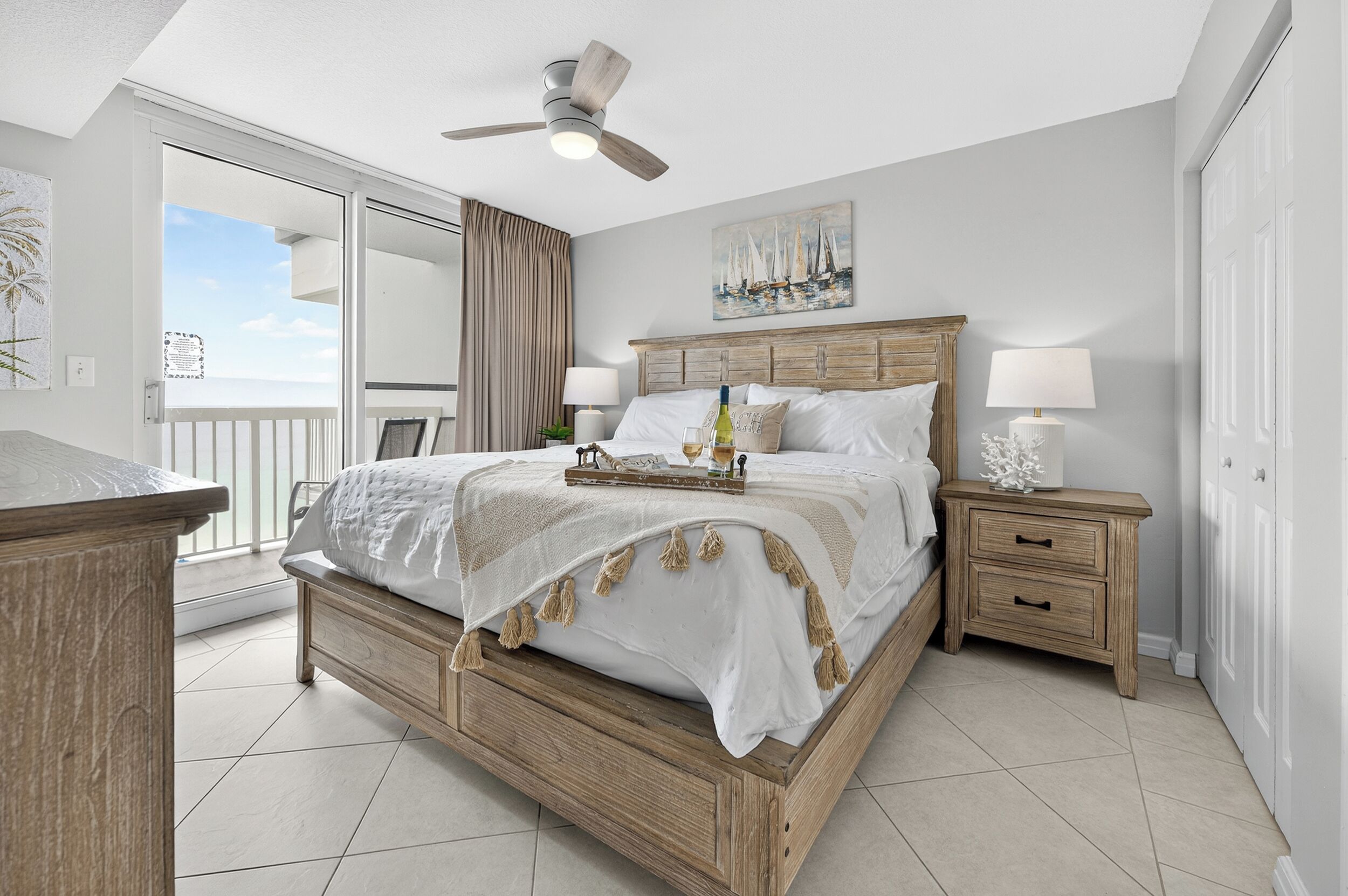 Una camera da letto con un letto di legno, due comodini, una ventola a soffitto, un quadro e vista sull'esterno.