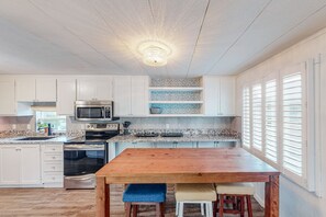 Enjoy meals in this kitchen with a central island and dining table, featuring a stainless steel oven and microwave.