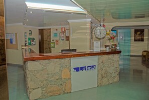 Una recepción con una base de piedra y un reloj encima.