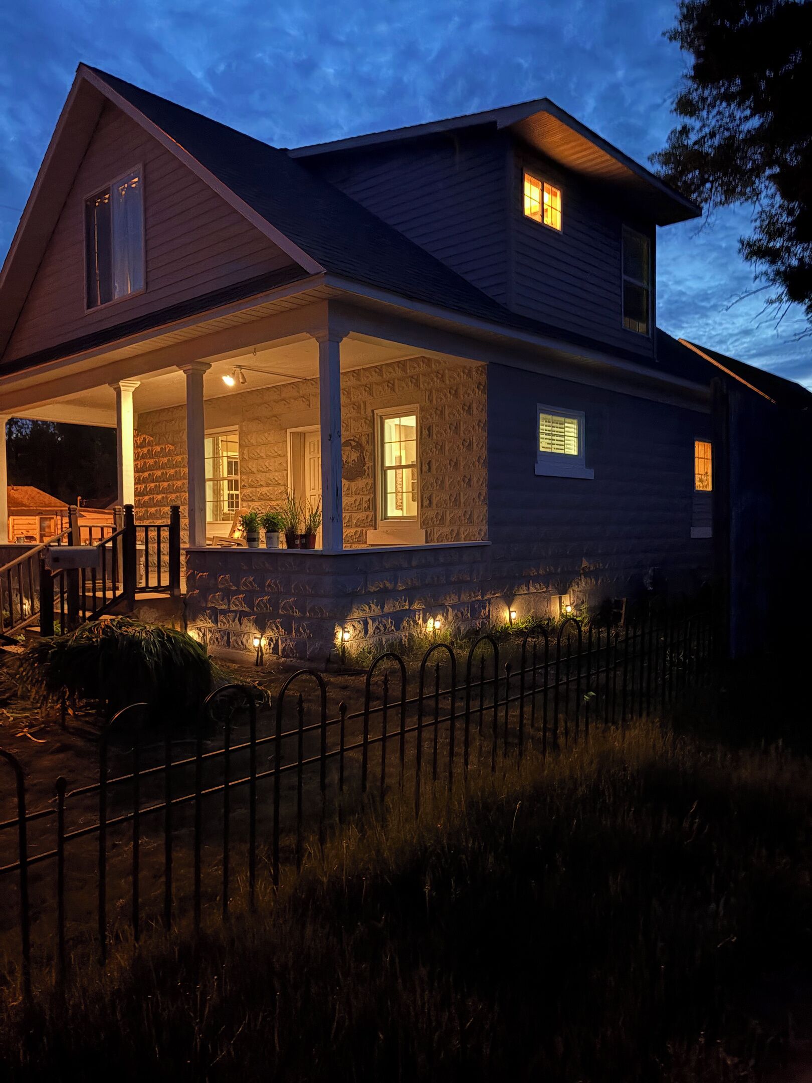 A two-story house with a covered porch and a stone foundation.