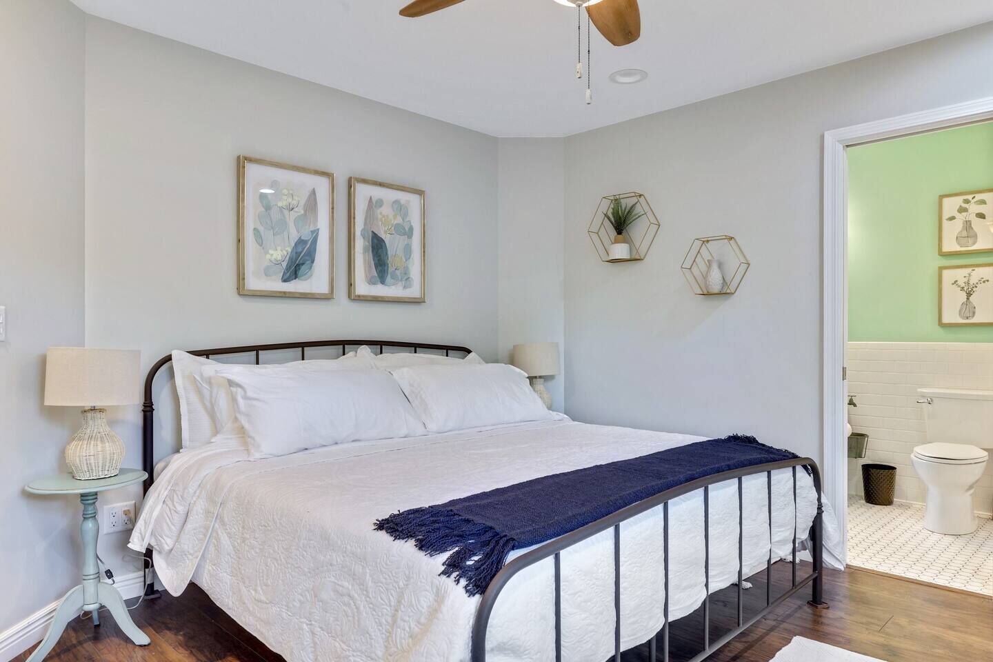 A bedroom with a bed, bedside tables, and a ceiling fan.