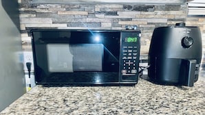 A kitchen with a microwave and a coffee maker on a granite countertop. - The Doze Off (Houston)