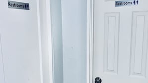 Two white doors with 'Restrooms' signs, one with a male and female symbol and the other with a male symbol only. - The Doze Off (Houston)