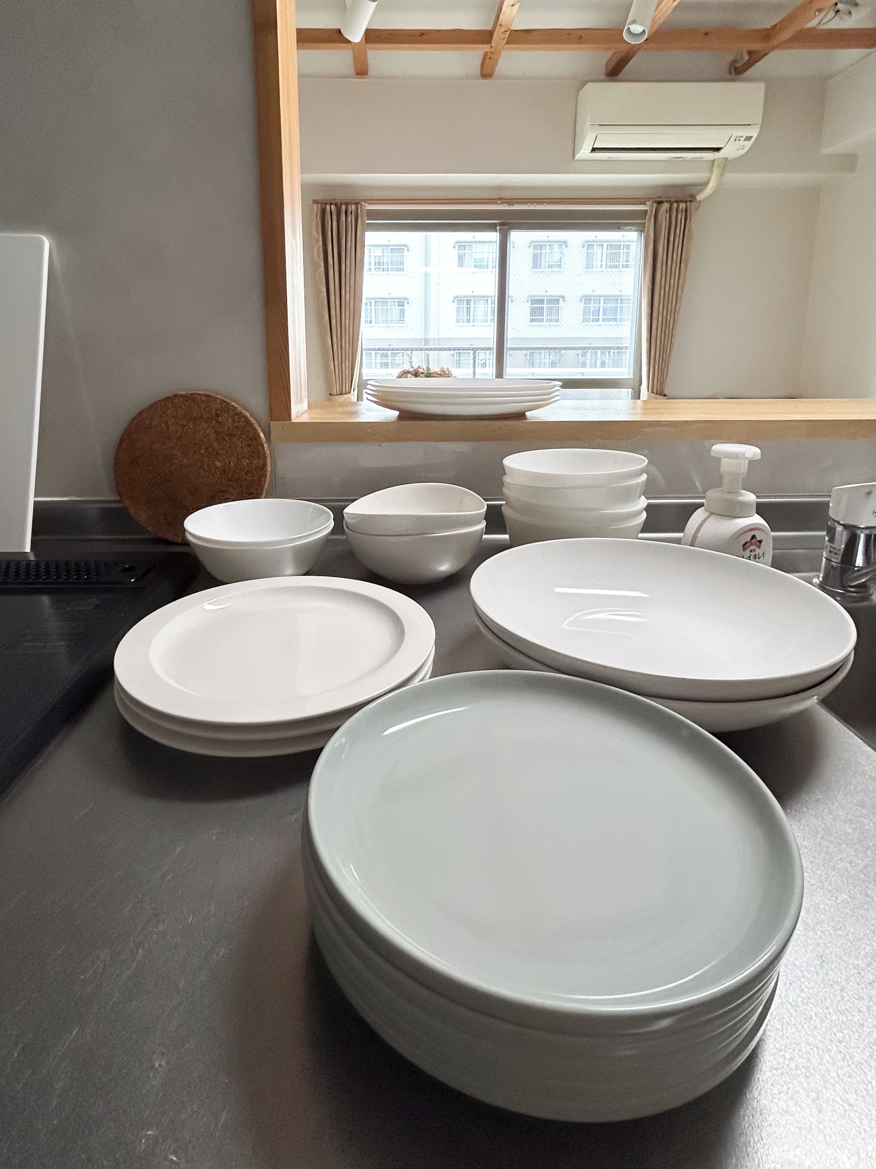 A kitchen with a window, a sink, and a countertop with stacked plates.