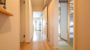 Un pasillo con suelo de madera y paredes blancas que da a varias habitaciones.