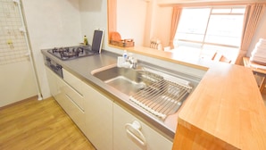 Una cocina con estufa a gas, pileta de acero inoxidable y encimera de madera.