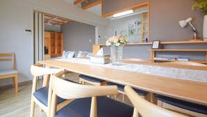 Un comedor con una mesa de madera, sillas y un jarrón con flores.