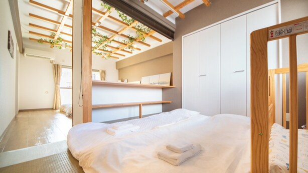 Un dormitorio con una cama grande, vigas de madera, una estantería con cuadros y un armario.