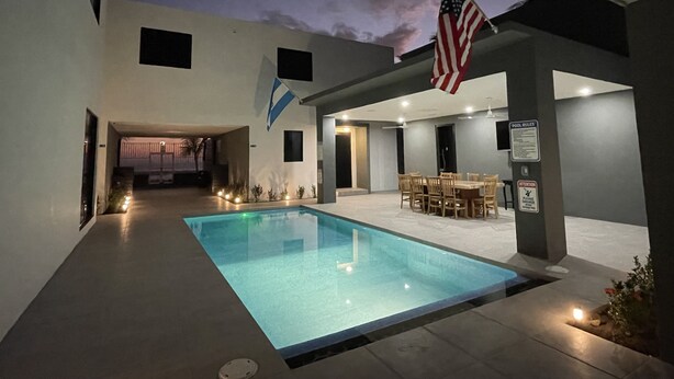 Zona de piscina con patio, bandera estadounidense y cartel de normas de la piscina.