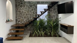 Una escalera moderna con pared de piedra, un televisor de pantalla plana y un pequeño jardín interior.