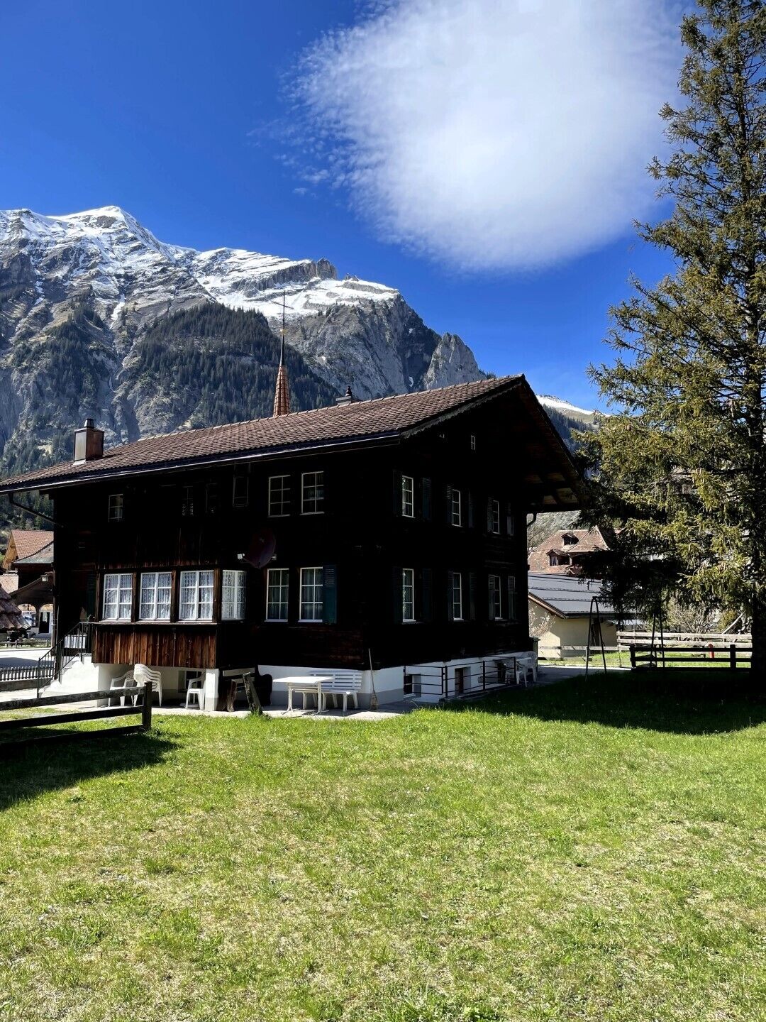 A traditional chalet with a sloped roof, multiple windows, and a small porch area.