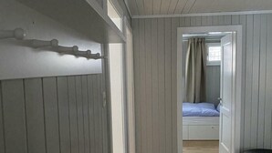 A bedroom with a bed, a window with curtains, and a door leading to another room. - "Mezzanine floor" - 4 1/2 room vacation apartment - in the "Chalet Baergli" (Kandersteg)