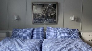 A bed with blue checkered bedding, a framed picture on the wall, and bedside lamps. - "Mezzanine floor" - 4 1/2 room vacation apartment - in the "Chalet Baergli" (Kandersteg)