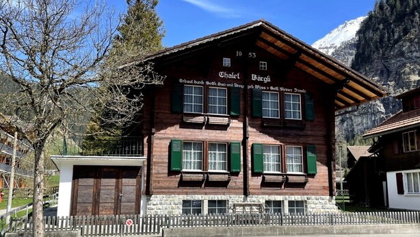 A traditional chalet with a stone facade, green shutters, and a wooden roof. - "Mezzanine floor" - 4 1/2 room vacation apartment - in the "Chalet Baergli" (Kandersteg)