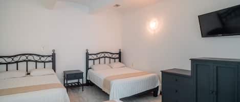 A bedroom with two beds, a nightstand, a dresser, and a TV on the wall.